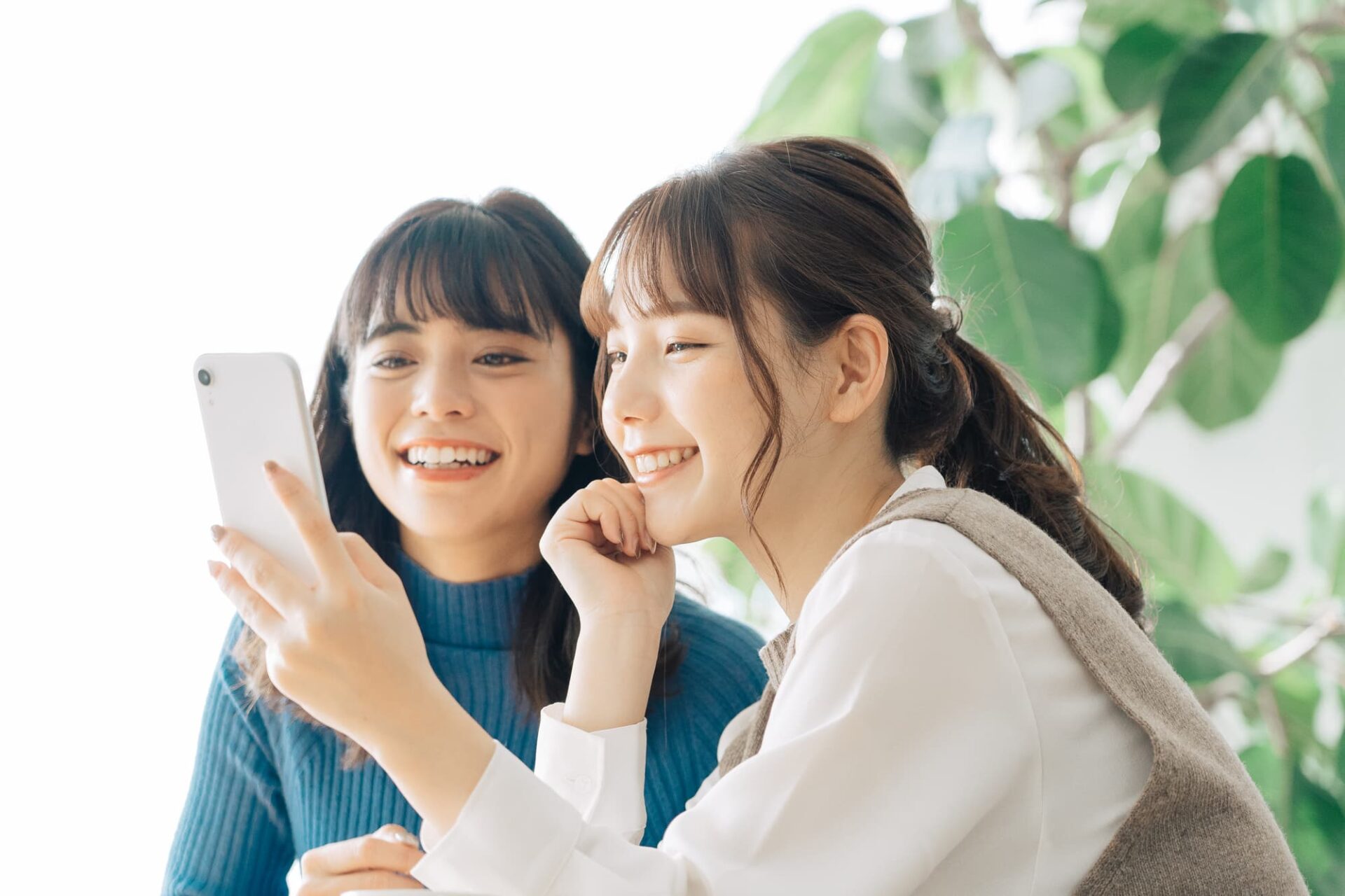 スマホを見ながら楽しそうに会話する二人の女性