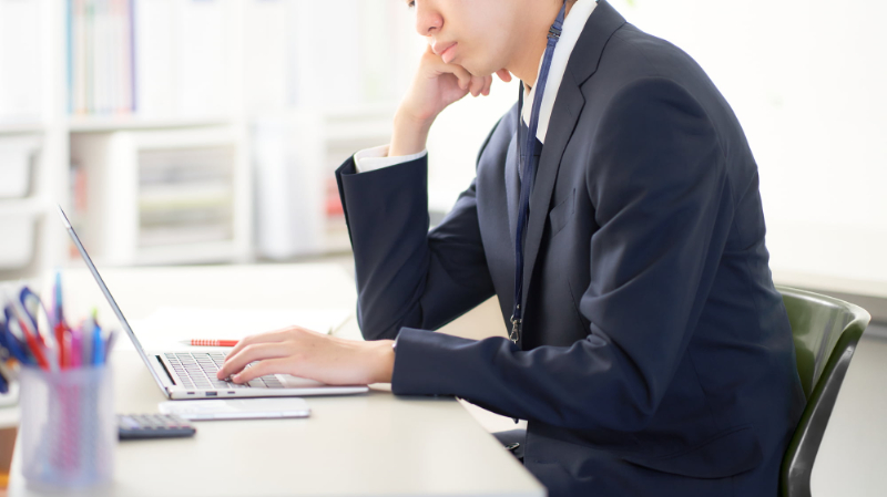 顎関節症の悪化の原因になる頬杖をついてパソコンをする男性