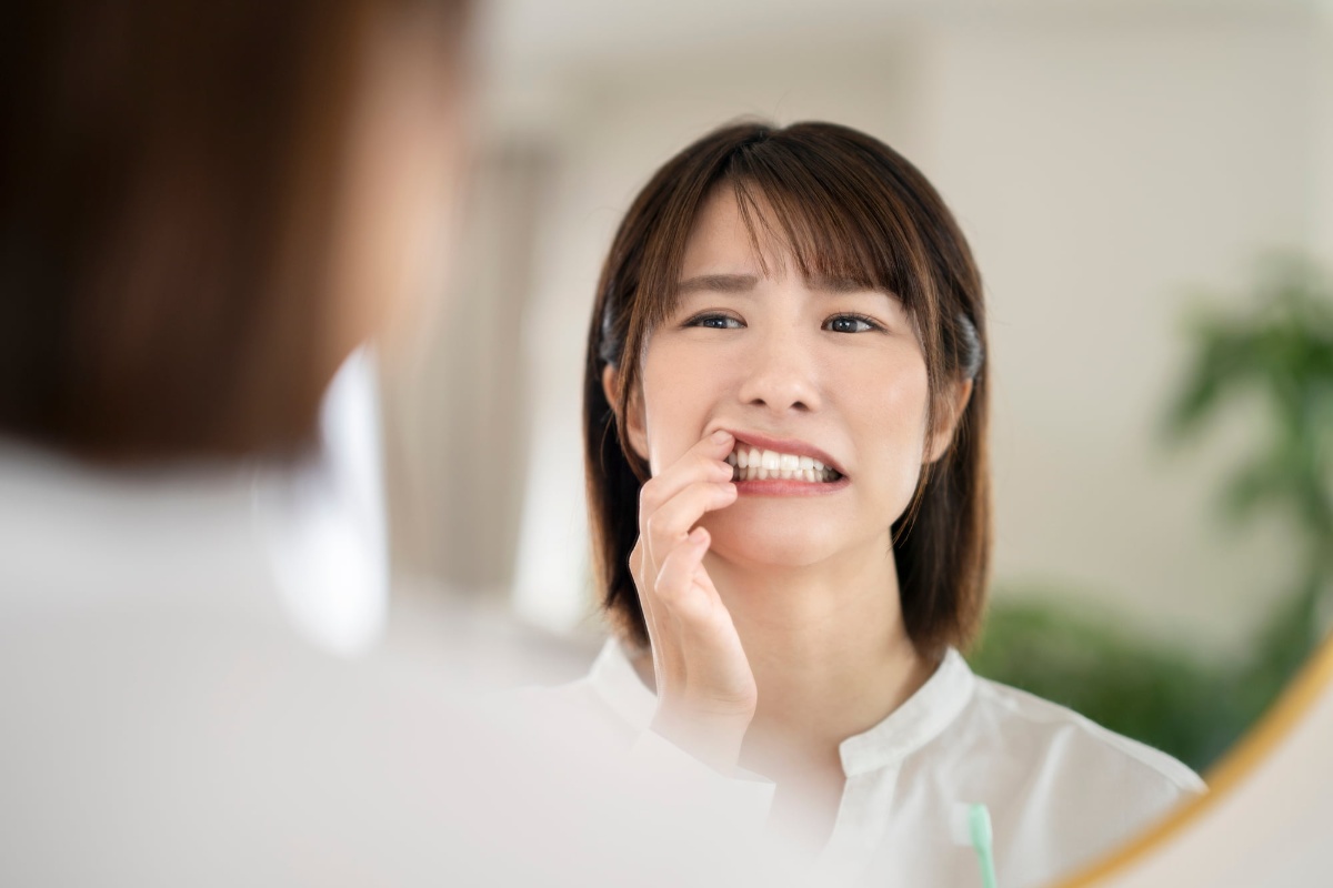 セラミック治療後に痛む歯茎を鏡で確認する女性