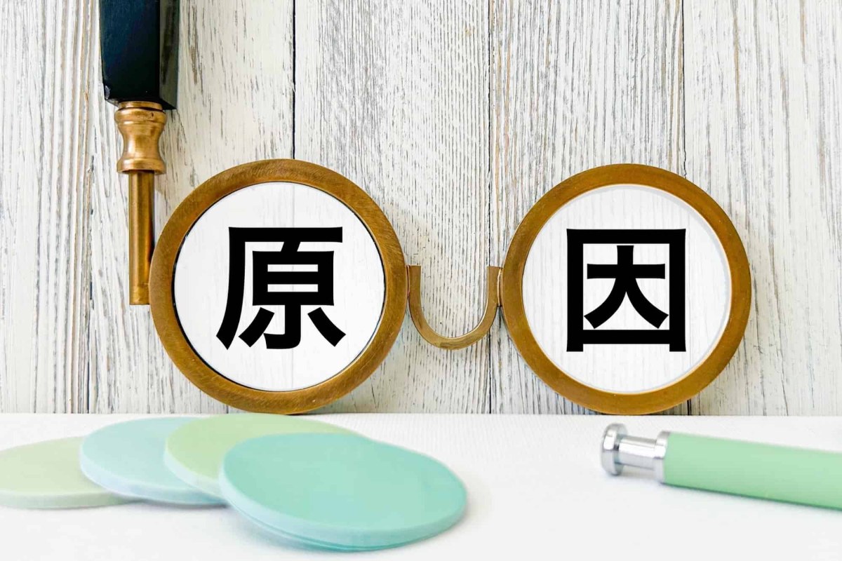 原因の文字の書かれた手持ちメガネ