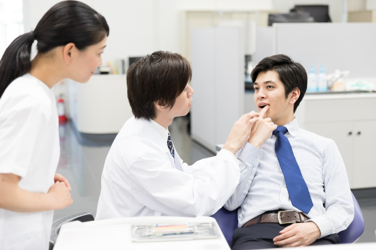セラミック治療後に歯茎が痛んで歯科医に診てもらう男性